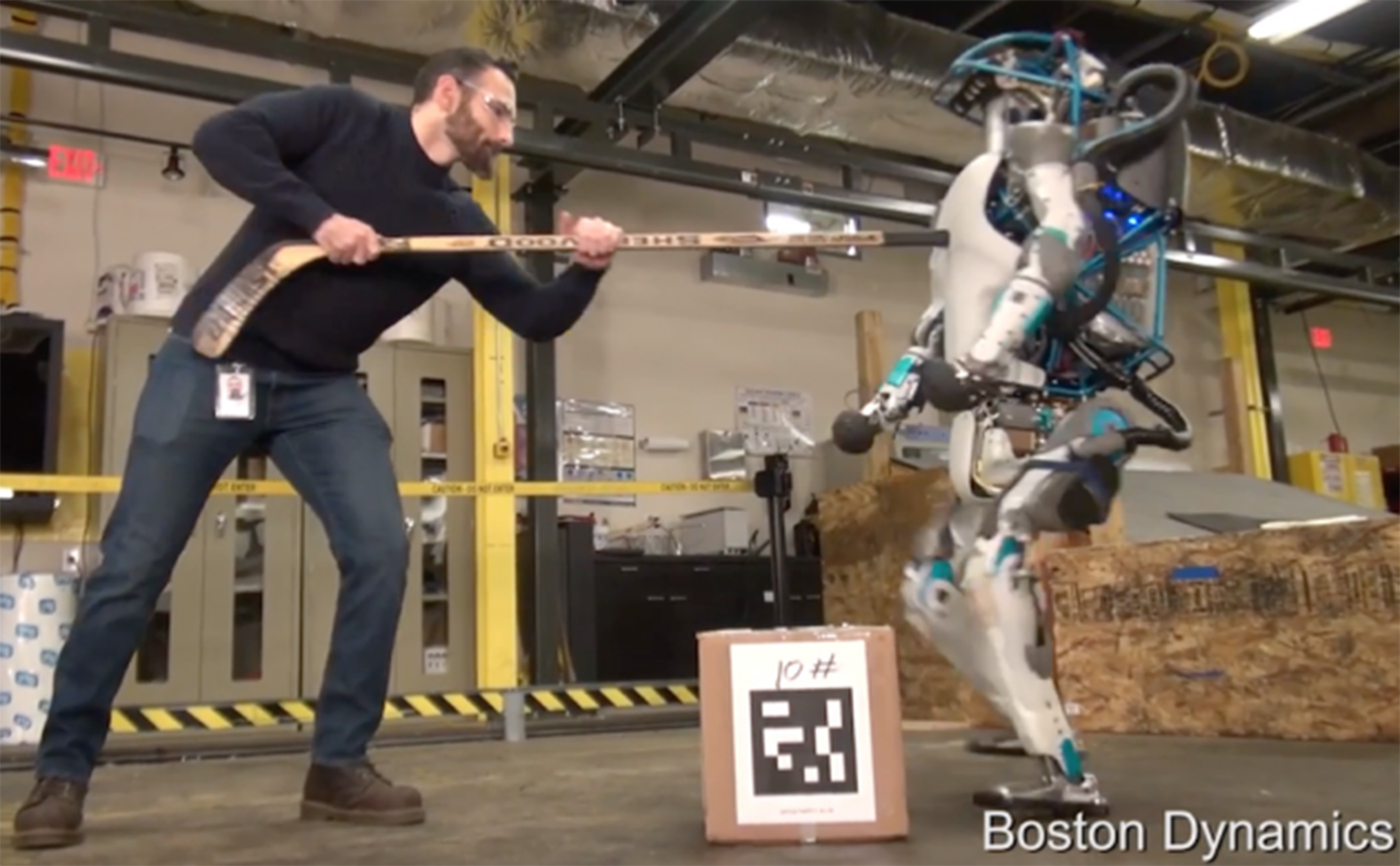 An engineer prods the robot, Atlas, with a hockey stick