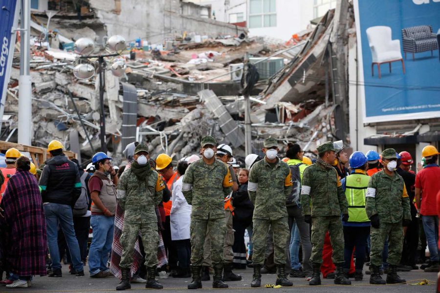 CORRECTS TO CLARIFY SITUATION WAS AN EVACUATION - Rescue workers and volunteers stand in the middle of the street after an earthquake alarm sounded and a small tremor was felt during rescue operations at the site of a collapsed building in Roma Norte, in Mexico City, Saturday, Sept. 23, 2017. All rescue workers atop the rubble were able to evacuate safely via an adjacent building. (AP Photo/Rebecca Blackwell)