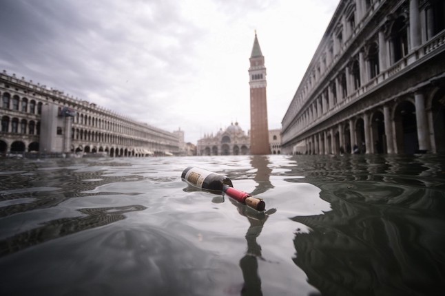 A general view shows a bottle of wine floating on the water of the flooded St. Mark's Square, with St. Mark's Basilica (Rear L) and the Bell Tower on November 15, 2019 in Venice, two days after the city suffered its highest tide in 50 years. - Flood-hit Venice was bracing for another exceptional high tide on November 15, as Italy declared a state of emergency for the UNESCO city where perilous deluges have caused millions of euros worth of damage. (Photo by Filippo MONTEFORTE / AFP)