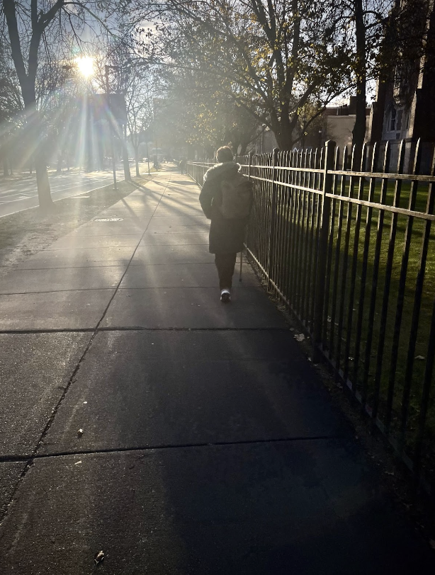 Aaron Mitchell walks down the Fenway sidewalk between Simmons residential and academic campus.